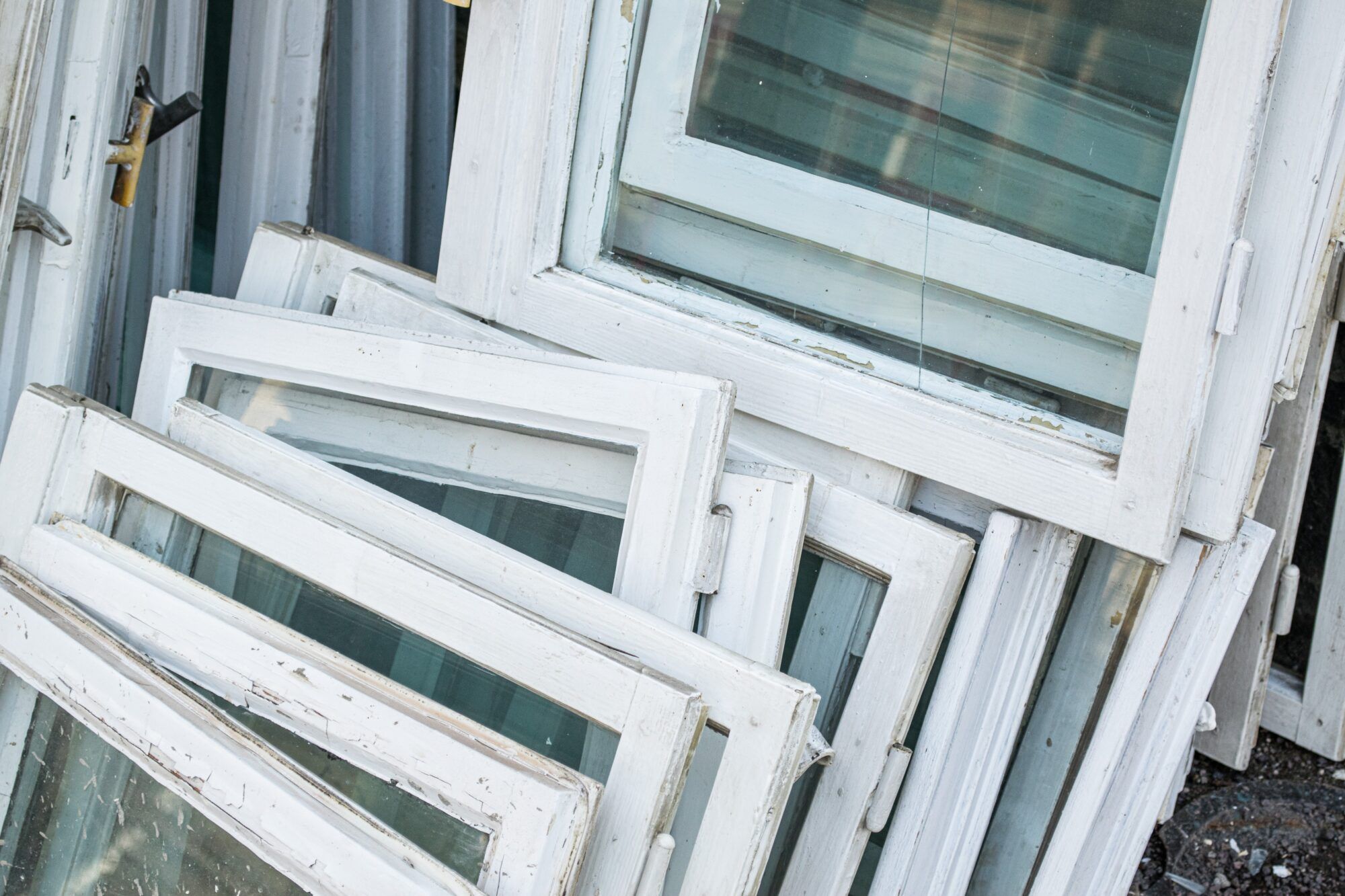 mehrere kaputte Holzfenster liegen auf einem Stapel