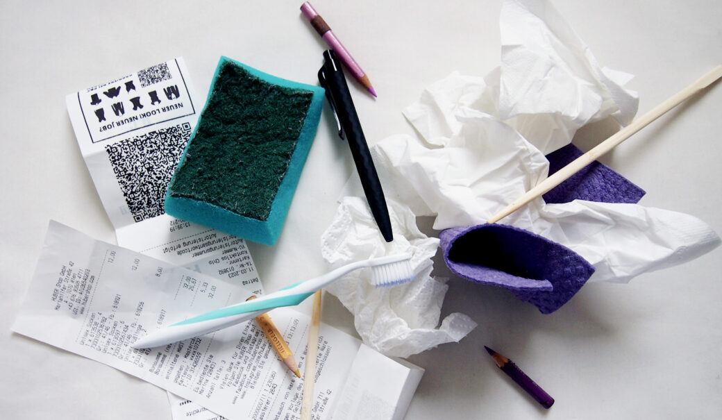 Auf dem Bild sieht man Kassenbons, Putzschwämme, Stifte, eine alte Zahnbürste